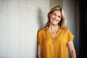 blonde woman wearing yellow shirt with smiling face